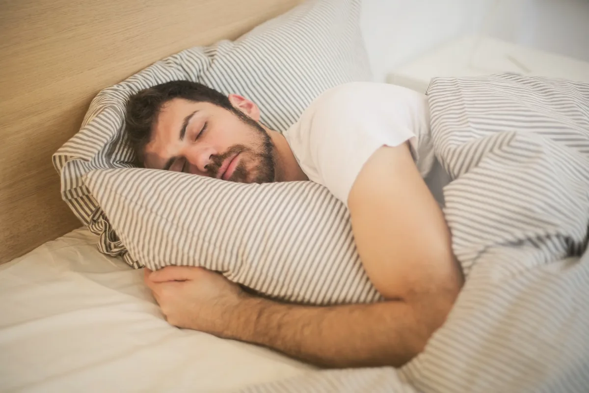 رجل نائم بهدوء في سريره — النوم الكافي ضروري لإنتاج التستوستيرون